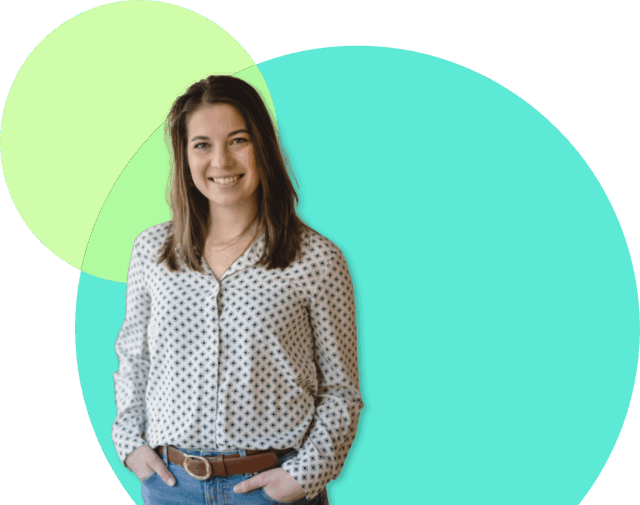 Eine lächelnde Frau mit braunem Haar, einer gemusterten Bluse und blauen Jeans steht mit den Händen in den Taschen da. Der Hintergrund, ideal für Weiterbildung für Führung und Kommunikation, besteht aus überlappenden hellgrünen und türkisfarbenen Kreisen.