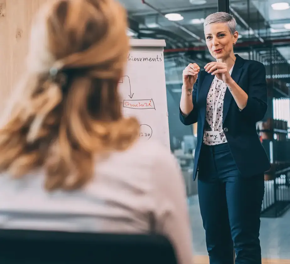 Trainerin im Seminarraum vor Flipchart