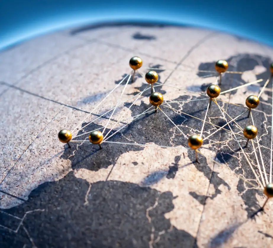Eine Nahaufnahme einer Karte mit durch Schnüre verbundenen goldenen Stecknadeln, die verschiedene Orte und Routen in Europa und den umliegenden Regionen anzeigen und so die Reichweite von Blanchard Global Partner auf einem Globus verdeutlichen.