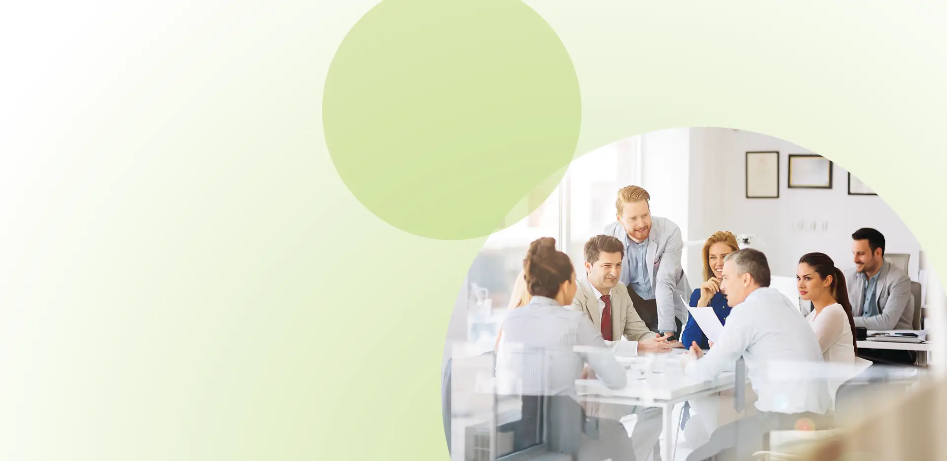 Eine Gruppe von Menschen sitzt und steht um einen Konferenztisch in einem hellen Büro und diskutiert – eine Szene, die das Thema „Teamentwicklung für Unternehmen“ verdeutlicht. Das Bild befindet sich in einem runden Rahmen vor einem hellgrünen, abstrakten Hintergrund.