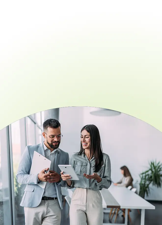 Ein Mann und eine Frau in Business-Casual-Kleidung unterhalten sich während eines Vertriebstrainings für Verkaufsteams in einem Büro über ein Tablet.